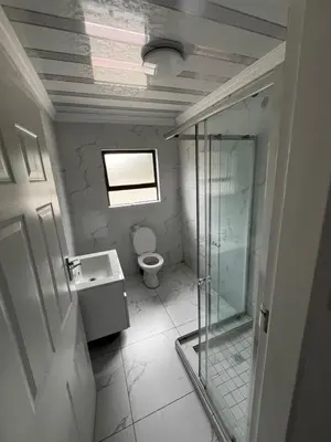 a bathroom with a glass shower and a toilet at Sunset Rest Guesthouse in Secunda