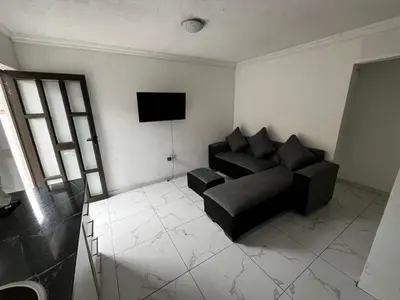 a living room with a black couch and a television at Sunset Rest Guesthouse in Secunda