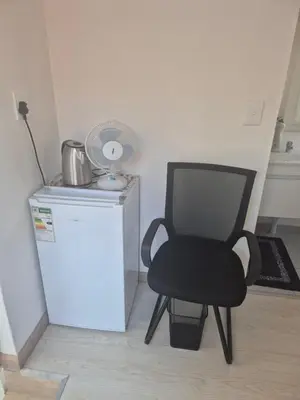 a black chair sitting next to a small refrigerator at TALOEM Private Room in Pretoria