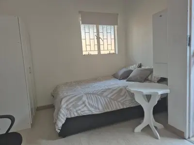a bedroom with a bed with a table and a window at TALOEM Private Room in Pretoria