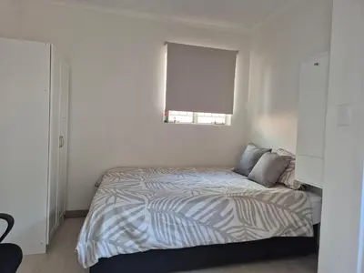 a white bedroom with a bed with a window at TALOEM Private Room in Pretoria
