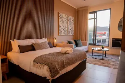 a bedroom with a large bed and a living room at 129 at Menlyn Maine in Pretoria