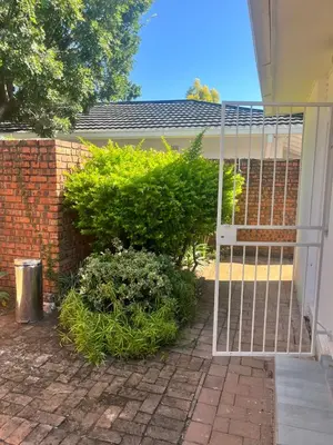 a gate in front of a building with a bush at Kwa George in Pretoria