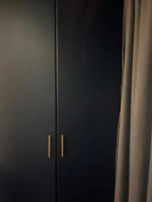 a black cabinet with gold handles next to a window at Kwa George in Pretoria