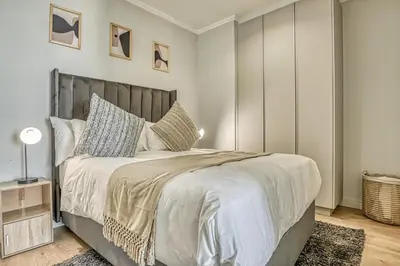 a bedroom with a large bed with white sheets and pillows at Golden Sunrise Suite at The Ellipse Waterfall in Midrand