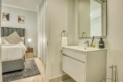 a white bathroom with a sink and a bed at Golden Sunrise Suite at The Ellipse Waterfall in Midrand
