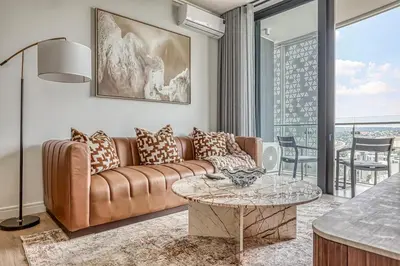 a living room with a couch and a table at Ellipse Waterfall Luxe Retreat in Midrand
