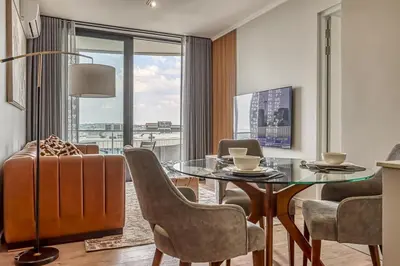 a living room with a glass table and chairs at Ellipse Waterfall Luxe Retreat in Midrand