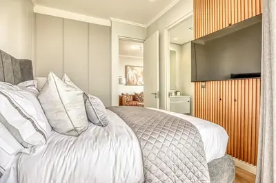 a bedroom with a bed with white sheets and pillows at Ellipse Waterfall Luxe Retreat in Midrand