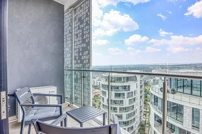 a balcony with two chairs and a view of a city at Ellipse Waterfall Luxe Retreat in Midrand