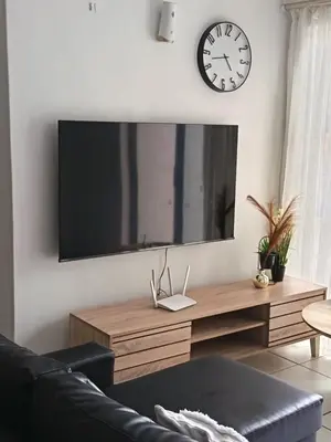 a living room with a black couch and a clock on the wall at The Blyde Cozy 1-Bedroom in Pretoria