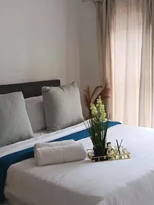 two beds with white sheets and a tray with flowers on it at The Blyde Cozy 1-Bedroom in Pretoria