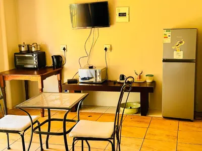 a kitchen with a table and a desk with a refrigerator at Bophelong Guest House in Witbank