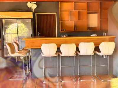 a bar with white stools in front of a counter at Bophelong Guest House in Witbank