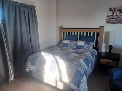 a bedroom with a bed with a blue and white comforter at One at Corridor in Witbank