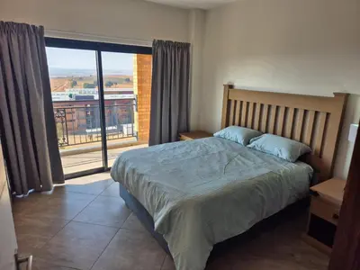 a bedroom with a bed and a large window at One at Corridor in Witbank