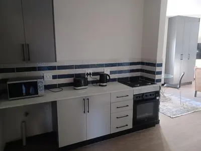 a kitchen with white cabinets and a stove top oven at One at Corridor in Witbank