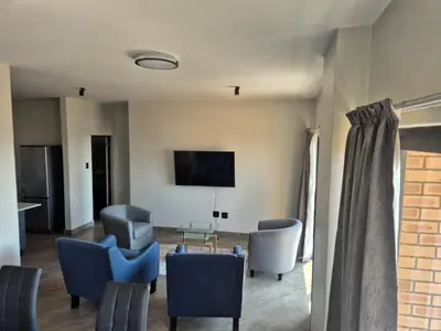 a living room with chairs and a flat screen tv at One at Corridor in Witbank