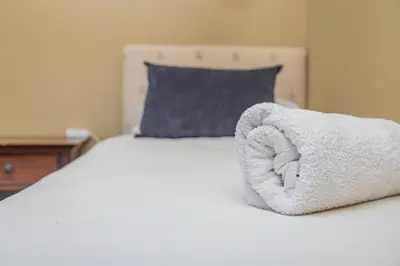 a white towel on a bed with a blue pillow at Bushveld Haven - Golf, Spa & Safari Lodge Stay in Warmbaths