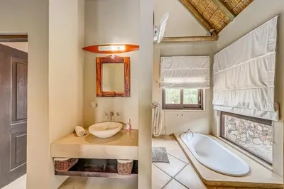 two images of a bathroom with a tub and a sink at Bushveld Haven - Golf, Spa & Safari Lodge Stay in Warmbaths
