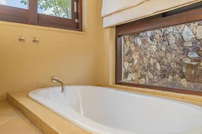 a bath tub in a bathroom with a window at Bushveld Haven - Golf, Spa & Safari Lodge Stay in Warmbaths