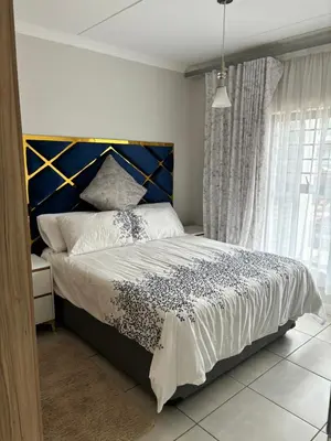 a bedroom with a large bed with a blue headboard at The Blyde Estate Apartments in Pretoria