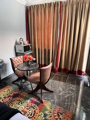 a living room with a table and chairs and curtains at MorningMist Boutique 27 Room 1 in Centurion