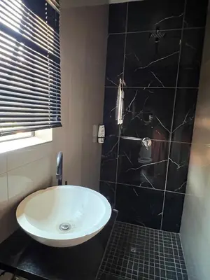 a bathroom with a white sink and a black wall at MorningMist Boutique 27 Room 1 in Centurion