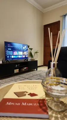 a living room with a table with a book and a tv at Elegant Self-Catering Witbank, 6 min Highveld Mall in Witbank