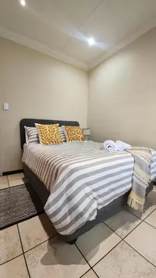 a bedroom with a large bed with striped blankets and pillows at Elegant Self-Catering Witbank, 6 min Highveld Mall in Witbank