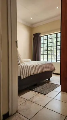 a bedroom with a bed and a large window at Elegant Self-Catering Witbank, 6 min Highveld Mall in Witbank