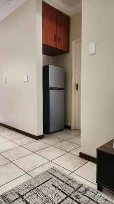 a kitchen with a refrigerator and a tile floor at Elegant Self-Catering Witbank, 6 min Highveld Mall in Witbank