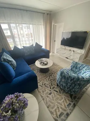 a living room with a blue couch and a tv at The Dream Escape At The Blyde - 2 Bedroom Apartment in Pretoria