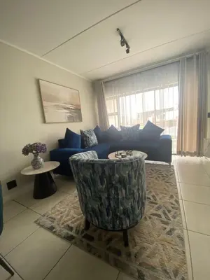 a living room with a blue couch and a table at The Dream Escape At The Blyde - 2 Bedroom Apartment in Pretoria