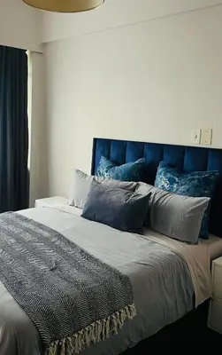 a bed with a blue headboard and pillows on it at Drostdy Hotel in Springs