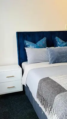 a bed with a blue headboard next to a night stand at Drostdy Hotel in Springs