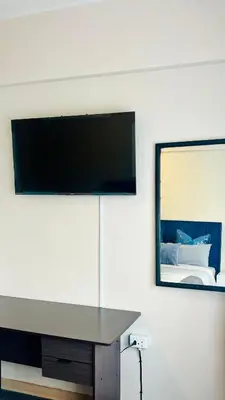 a flat screen tv on a wall with a desk at Drostdy Hotel in Springs