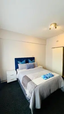 a bedroom with a large bed with a blue headboard at Drostdy Hotel in Springs