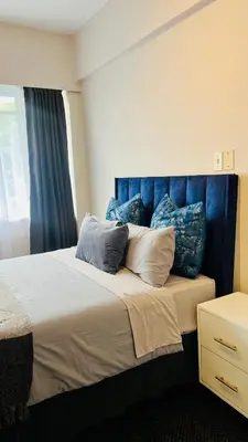 a bedroom with a bed with blue headboard and pillows at Drostdy Hotel in Springs