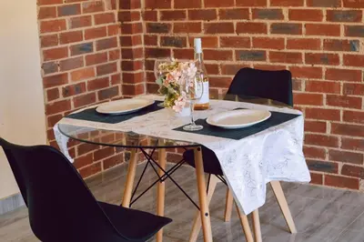 a table with chairs and plates and a brick wall at L a Grande deluxe in Benoni