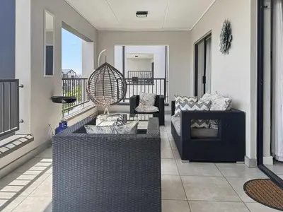a living room with two couches on a balcony at Resort style 1BR-Big balcony-Lagoon Luxury Spa in Midrand