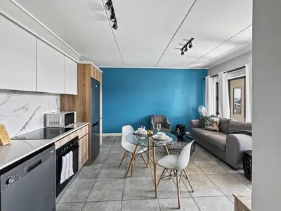 a kitchen and living room with a table and chairs at Resort style 1BR-Big balcony-Lagoon Luxury Spa in Midrand