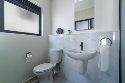 a white bathroom with a toilet and a sink at Alimama Spaces Whisken Haven in Midrand