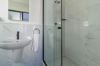 a bathroom with a glass shower and a sink at Alimama Spaces Whisken Haven in Midrand