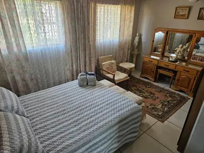 a bedroom with a bed and a chair and a mirror at Luxury Meets Convenience Near City & Travel Links in Pretoria