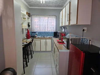 a kitchen with white cabinets and black counter tops at Luxury Meets Convenience Near City & Travel Links in Pretoria