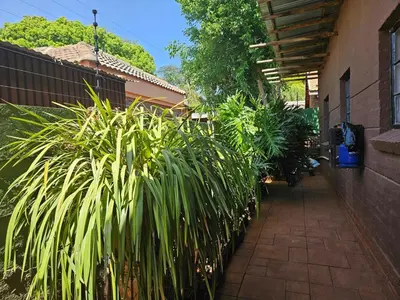 a fence with plants next to a building at Luxury Meets Convenience Near City & Travel Links in Pretoria