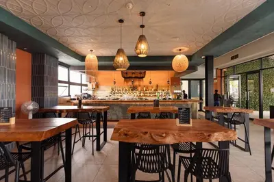 a restaurant with wooden tables and chairs and a bar at The Dream Escape At The Blyde - 2 Bedroom Apartment in Pretoria