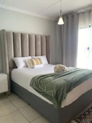 a bedroom with a large bed with a gray headboard at The Dream Escape At The Blyde - Lagoon Facing 3 Bedroom Apartment in Pretoria