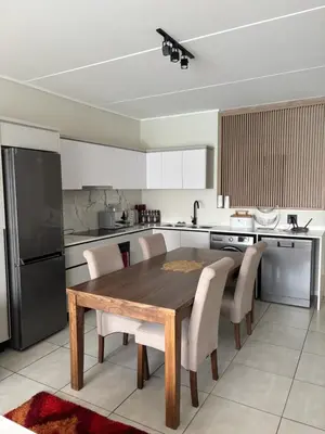 a kitchen with a wooden table and chairs and a refrigerator at The Dream Escape At The Blyde - Lagoon Facing 3 Bedroom Apartment in Pretoria